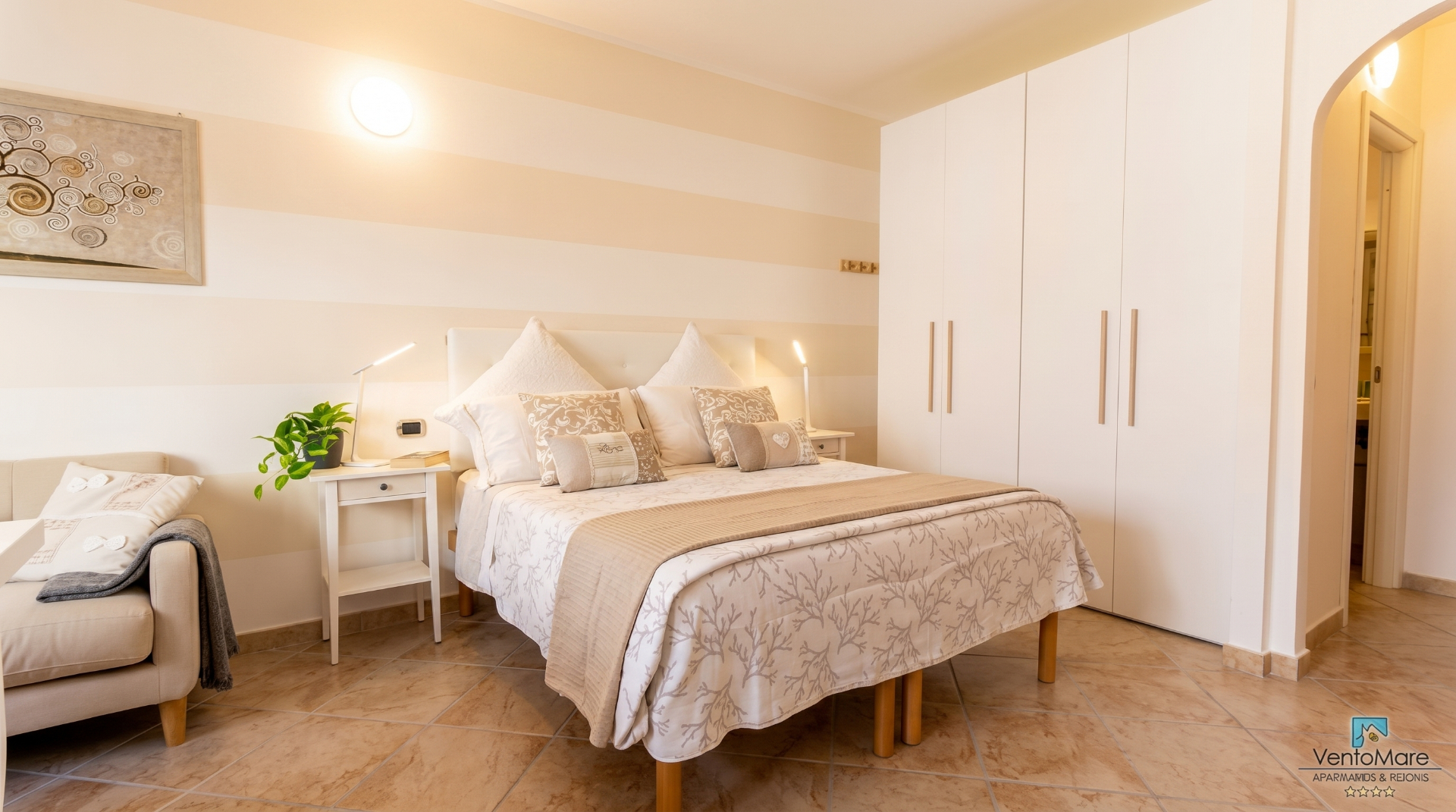 Camera da letto luminosa e accogliente in stile mediterraneo, con biancheria bianca, tazza di caffè e accappatoio